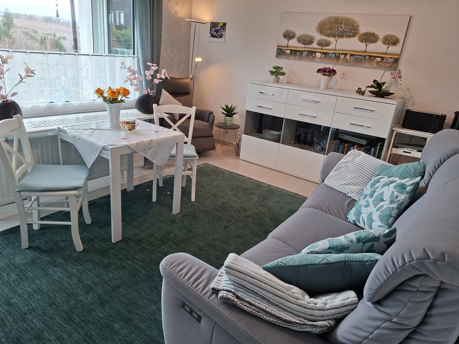 Wohnzimmer mit Sofa, Esstisch und Blick auf Balkon.