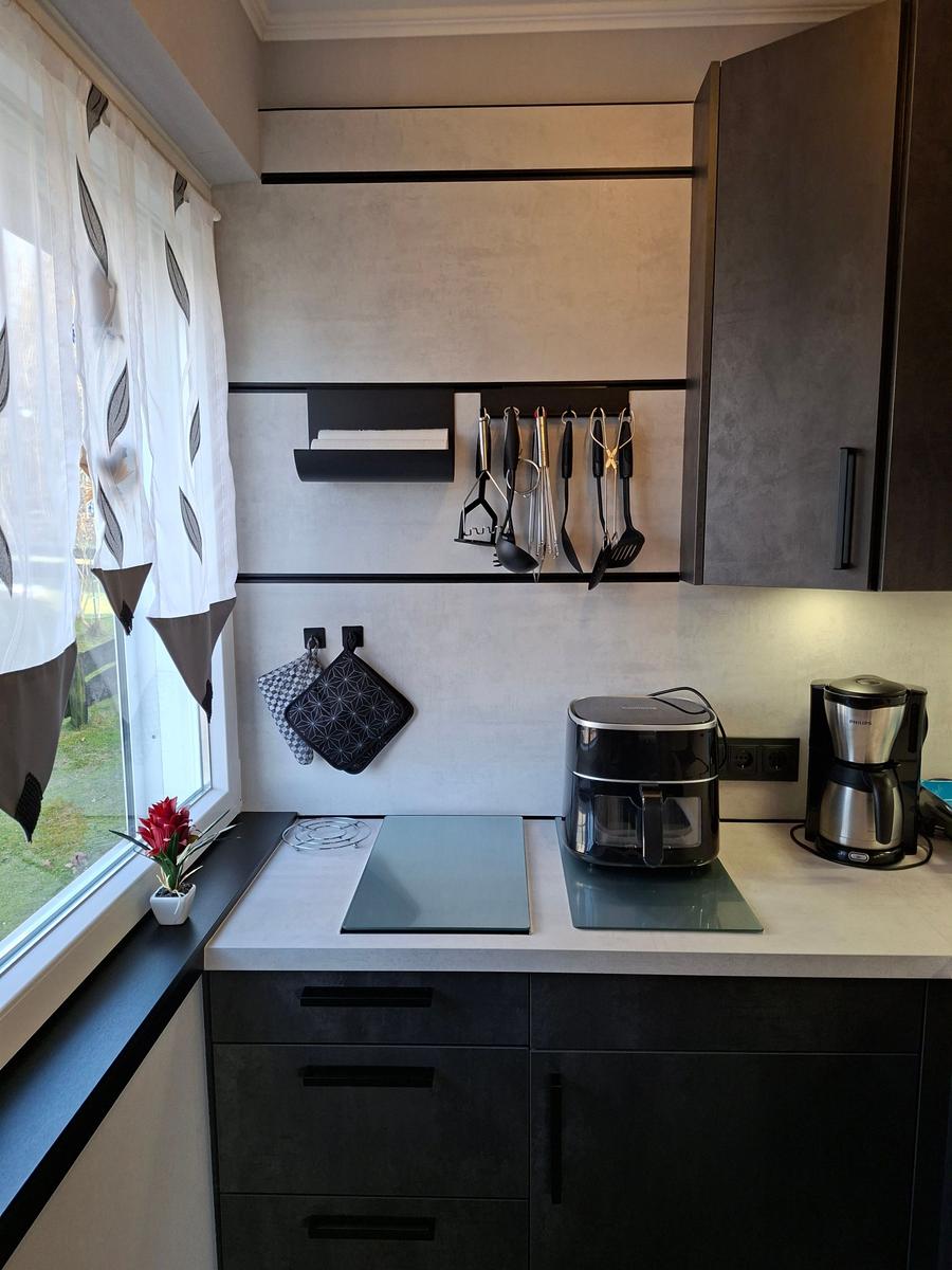 Küche mit Arbeitsplatte, Kaffeemaschine und Küchenutensilien an der Wand.