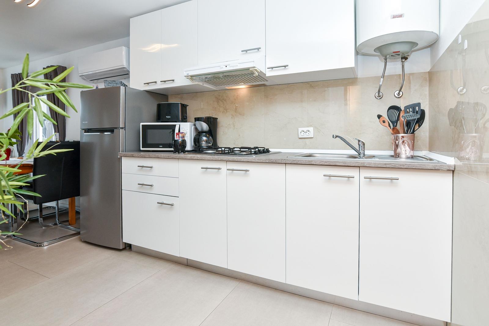 Moderne Küche mit weißen Schränken, Edelstahl-Kühlschrank und Küchenzeile.