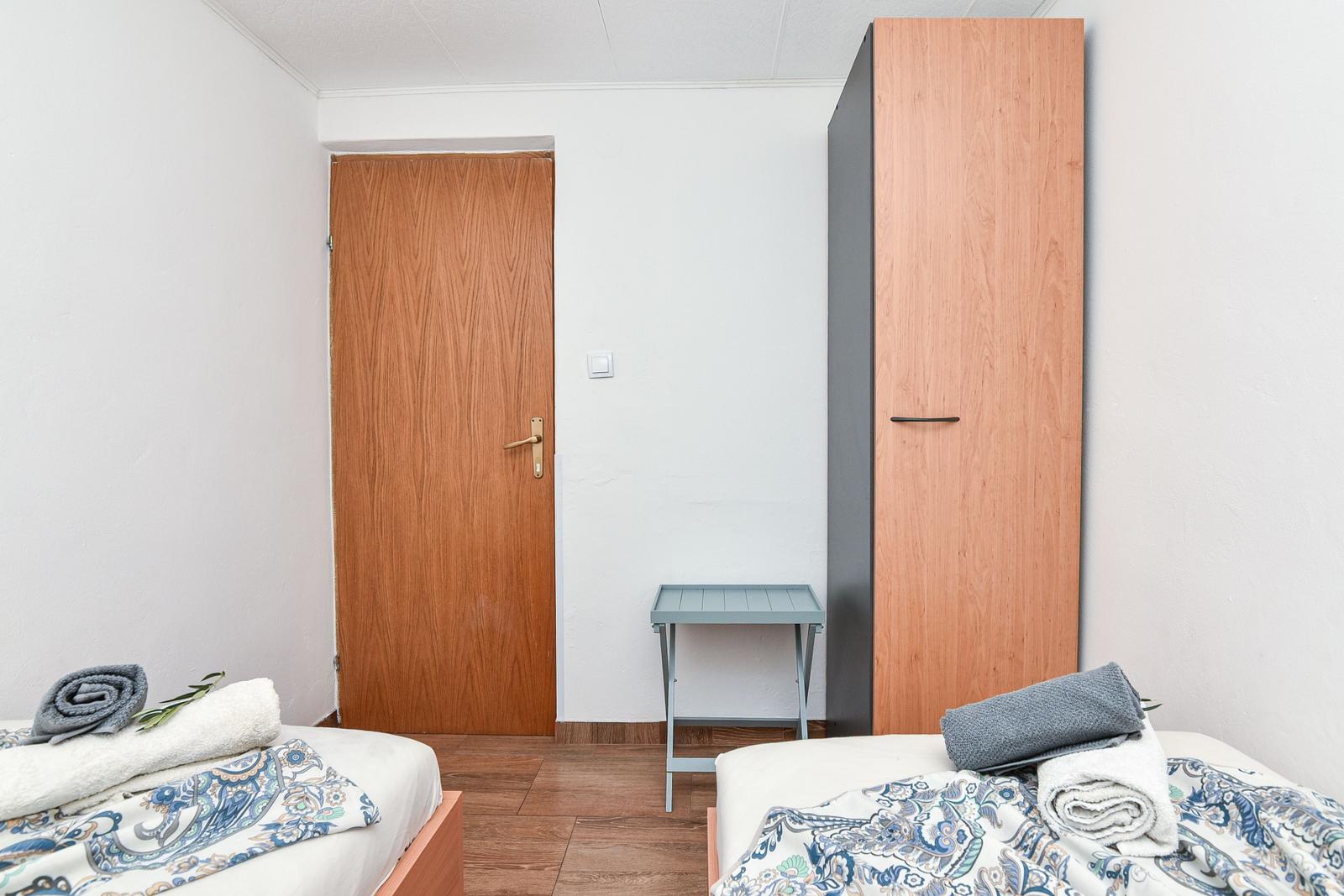 Zwei Betten mit Bettwäsche, Kleiderschrank und Tür im Zimmer.