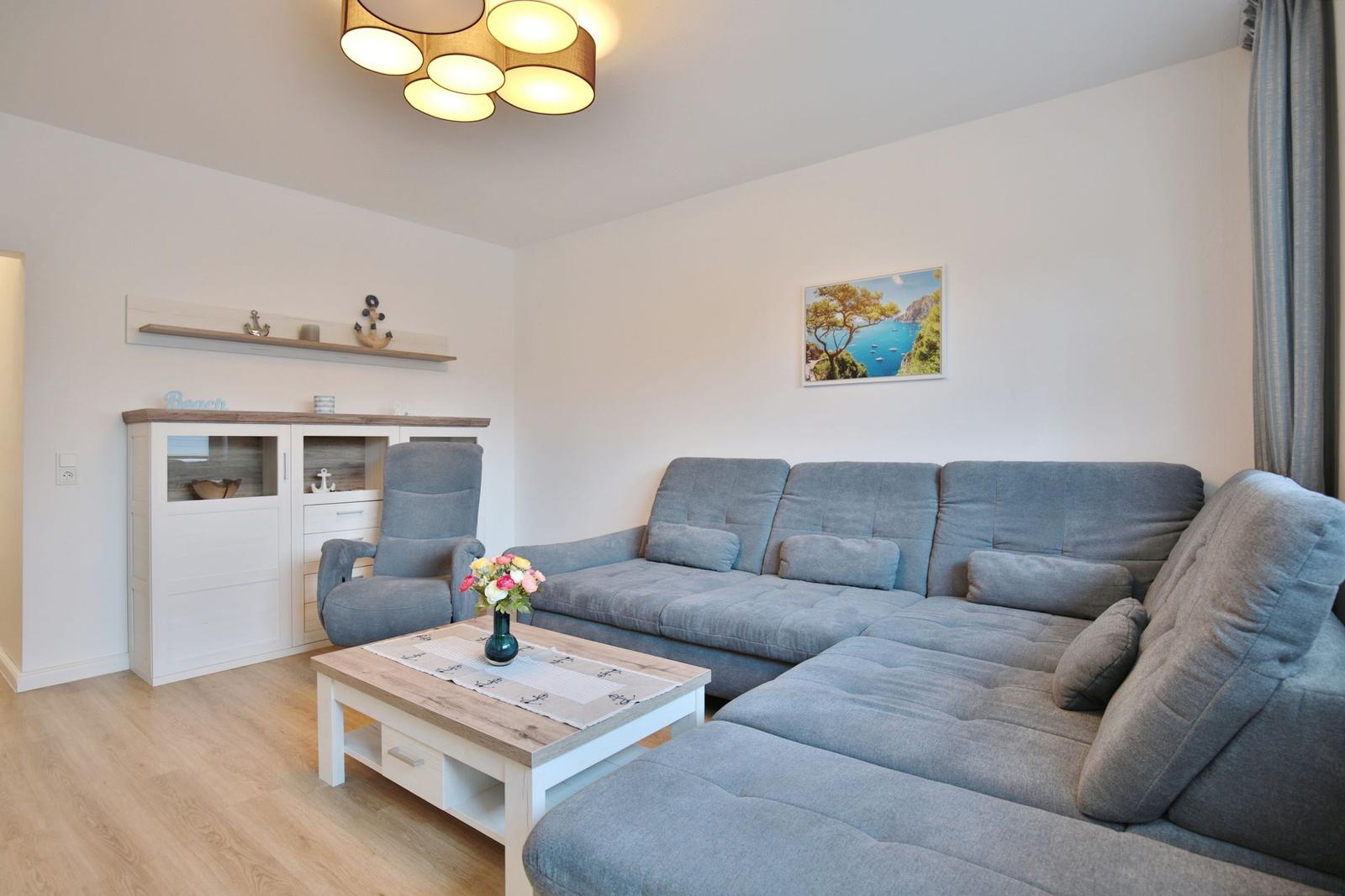 Wohnzimmer mit grauem Sofa, Holztisch und Wandbild.
