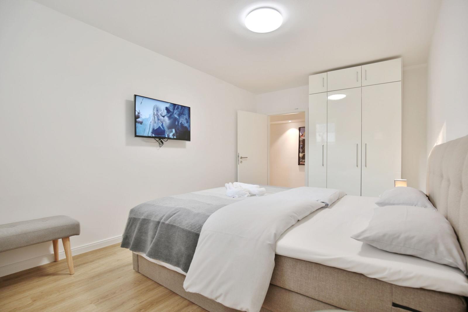 Schlafzimmer mit Bett, TV und Kleiderschrank.