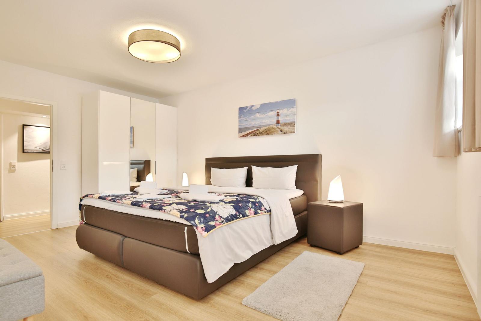 Schlafzimmer mit Bett, Nachttisch und Wandbild.