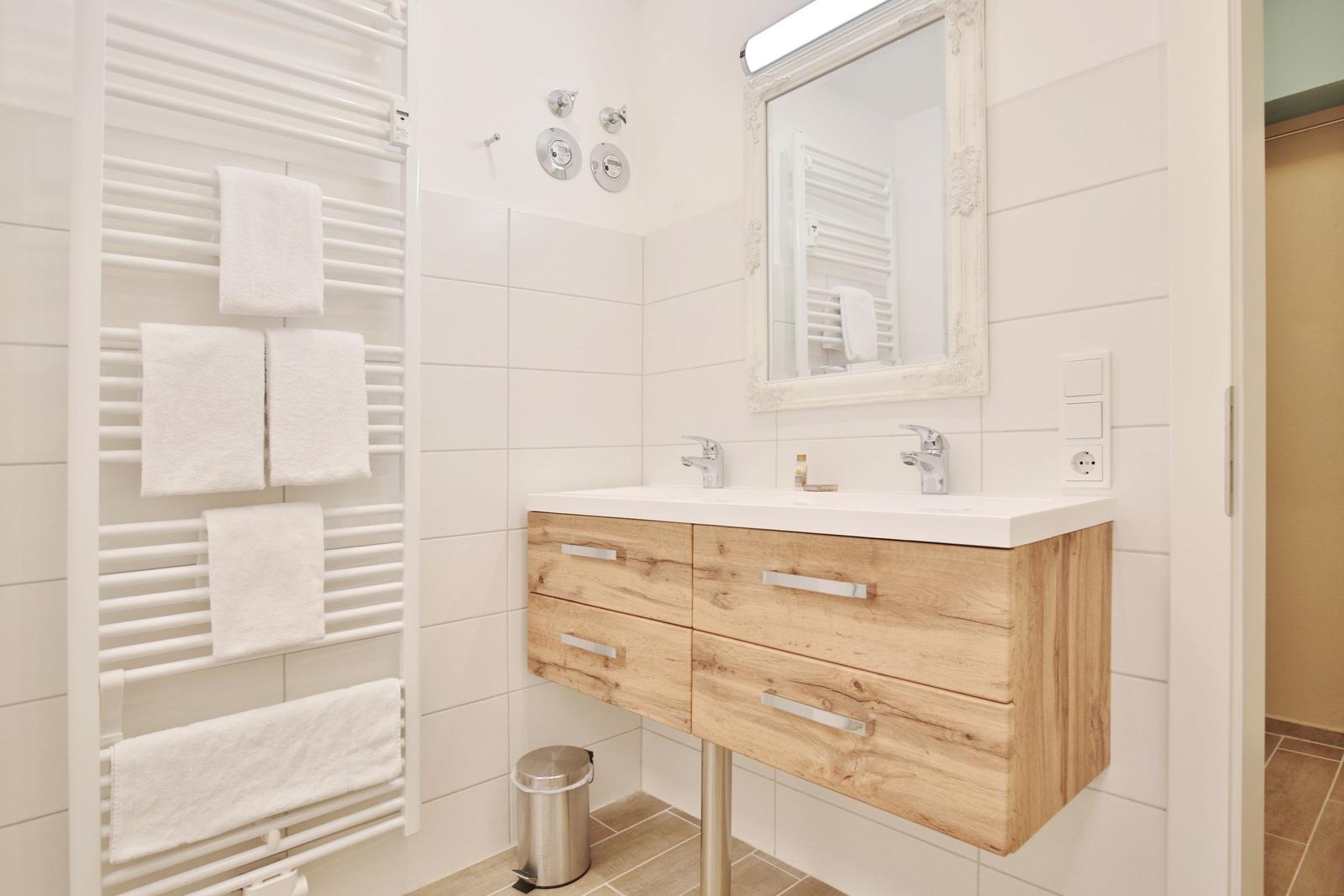 Badezimmer mit Holzwaschbecken, Spiegel und Handtuchheizung.
