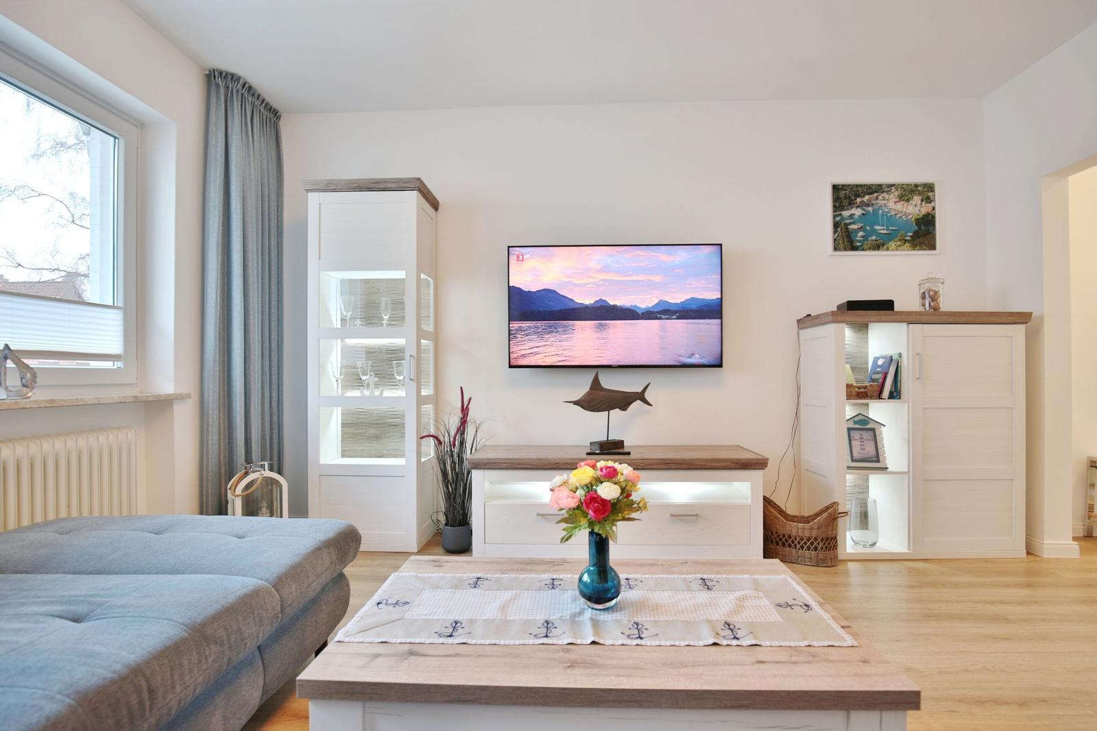 Wohnzimmer mit TV, Tisch, Sofa und Schränken.