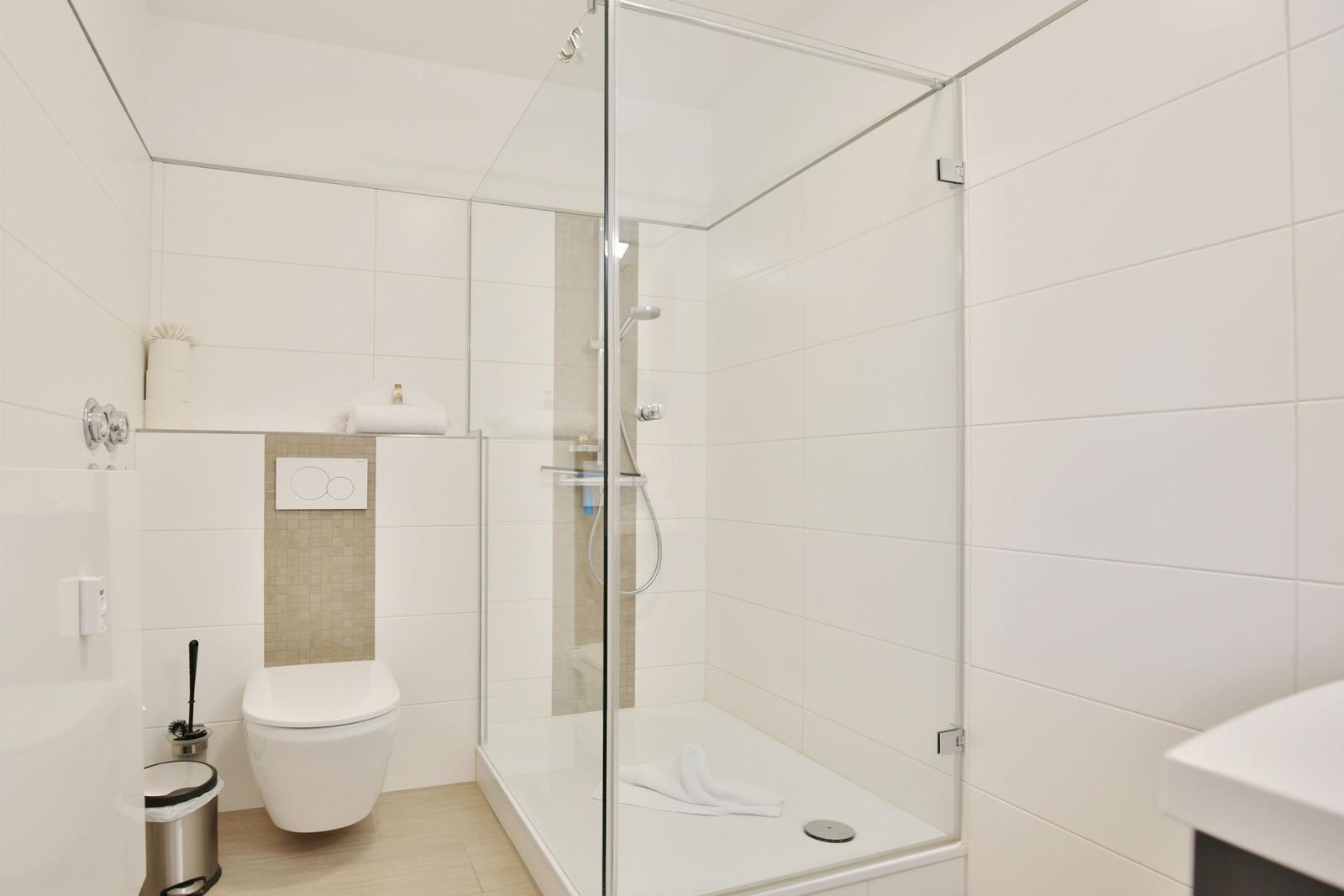Badezimmer mit Dusche, Toilette und Waschbecken.
