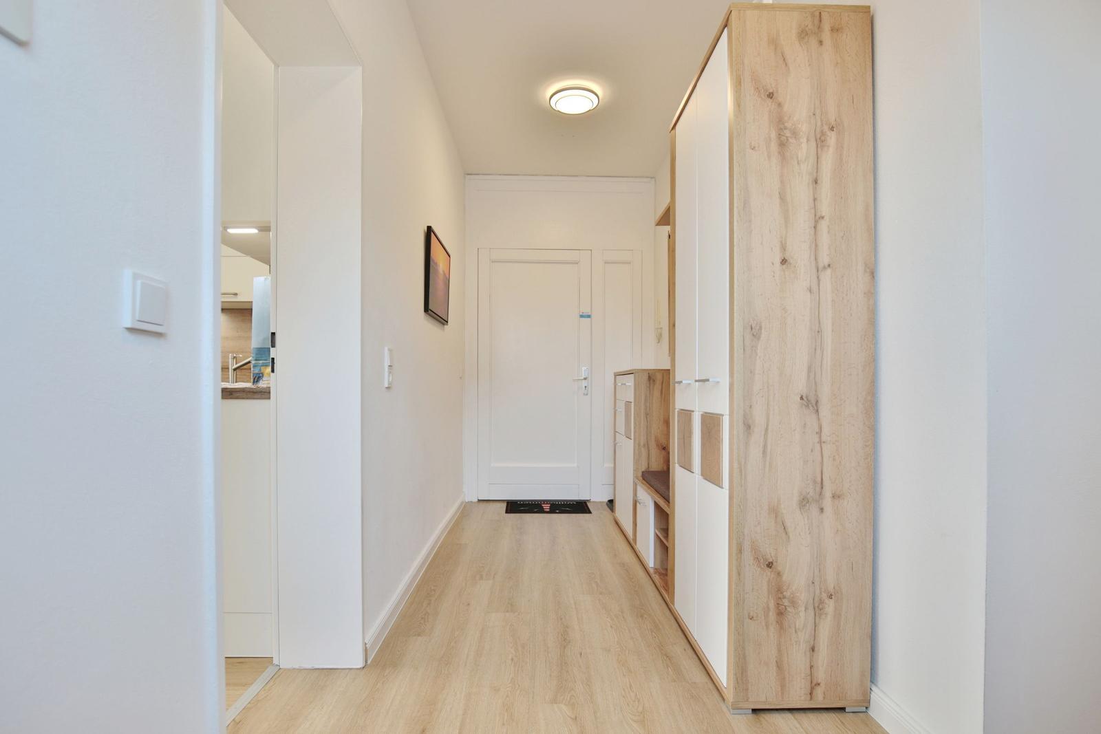 Flur mit Holzparkett, Kleiderschrank und Blick in die Küche.