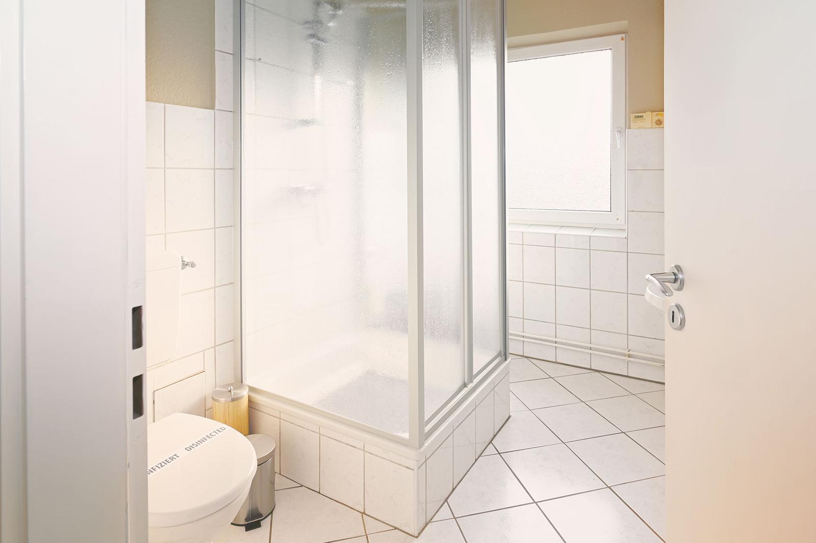 Badezimmer mit Dusche, Toilette und Fenster