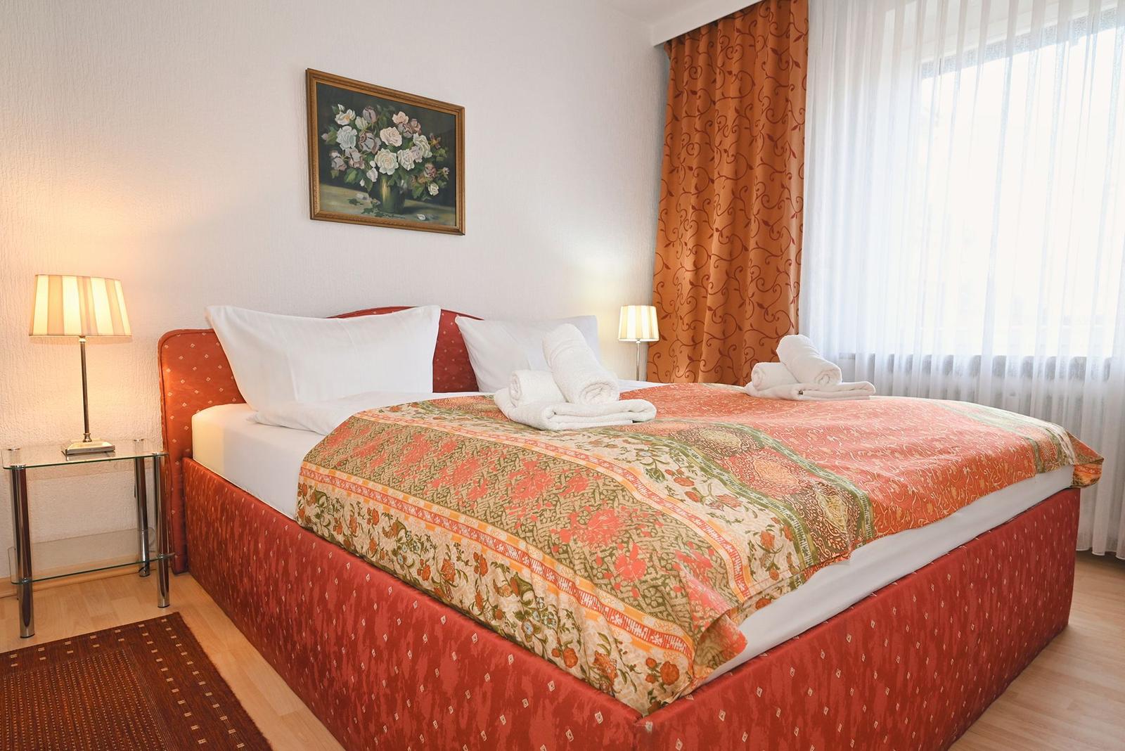 Schlafzimmer mit Bett, Vorhängen und Nachttisch