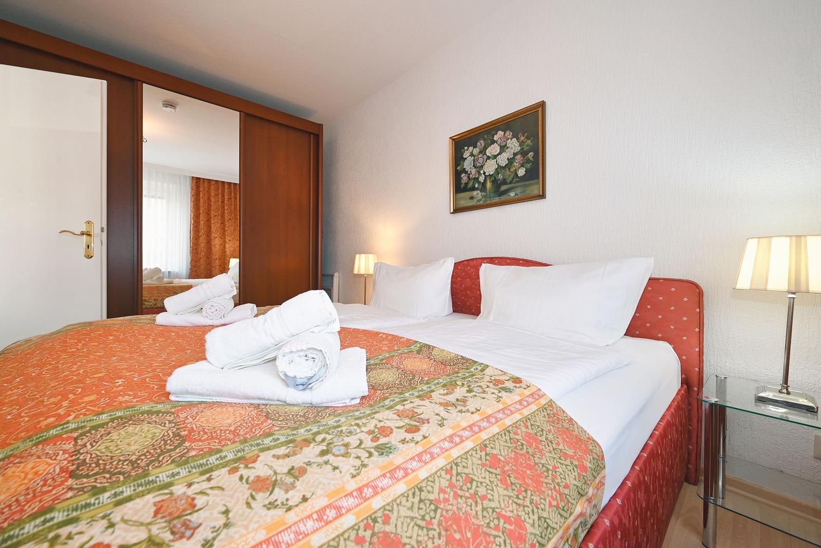 Schlafzimmer mit Bett, Nachttisch und Spiegeltüren.