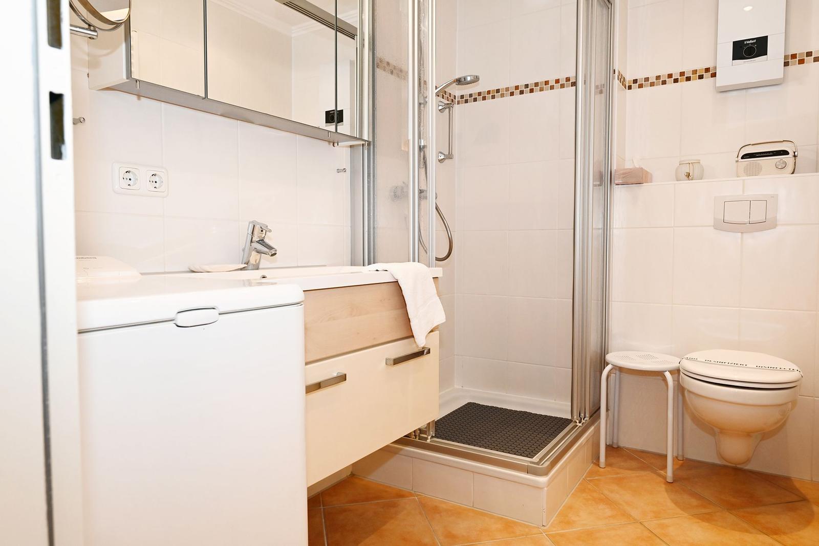 Badezimmer mit Dusche, Waschbecken und Toilette.