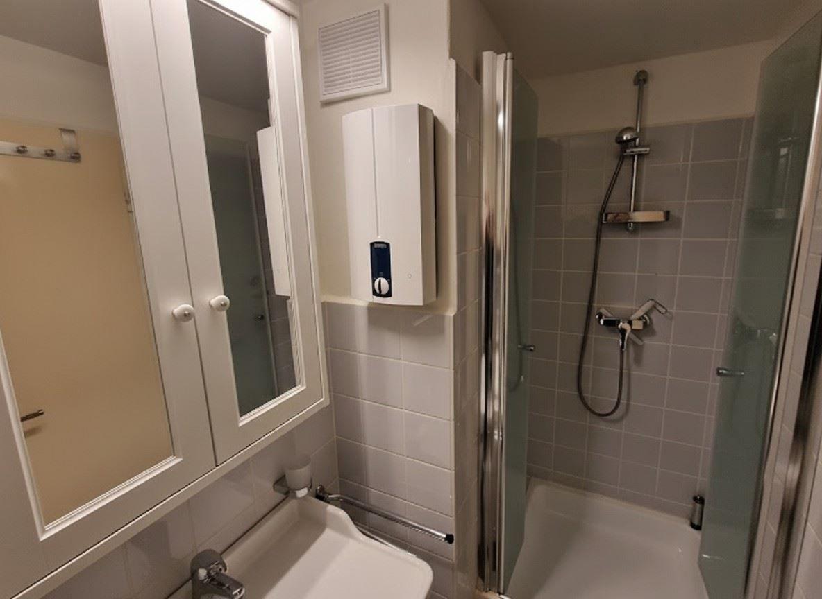 Badezimmer mit Dusche, Waschbecken und Spiegelschrank