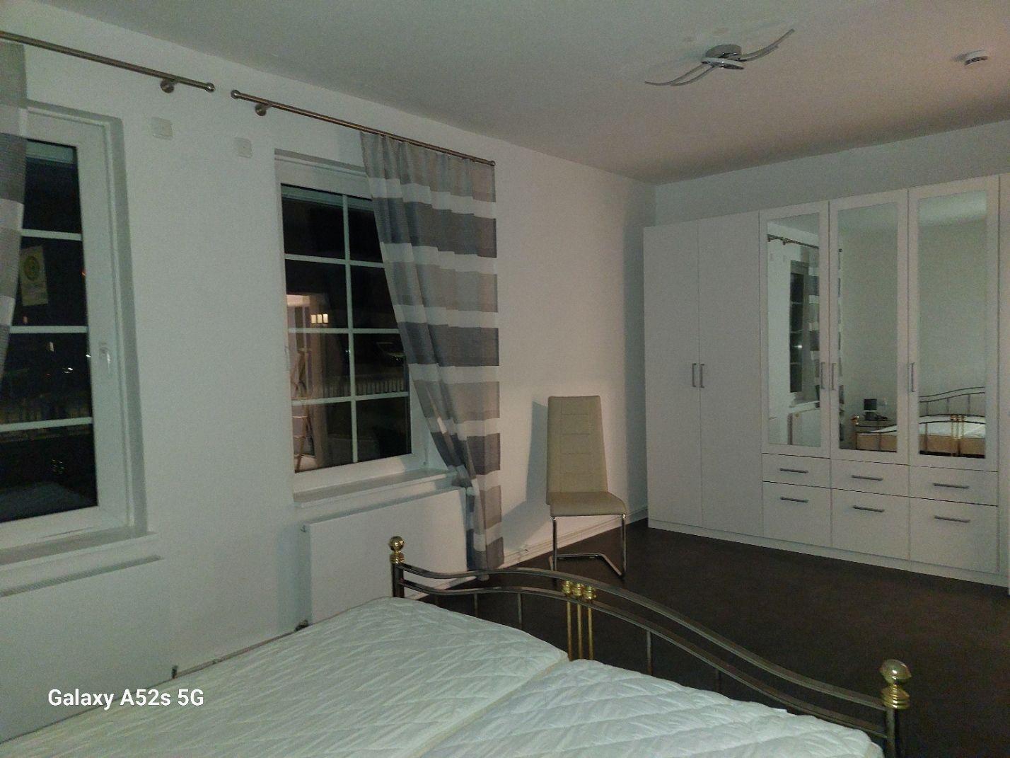 Schlafzimmer mit Bett, Kleiderschrank und Fenster.