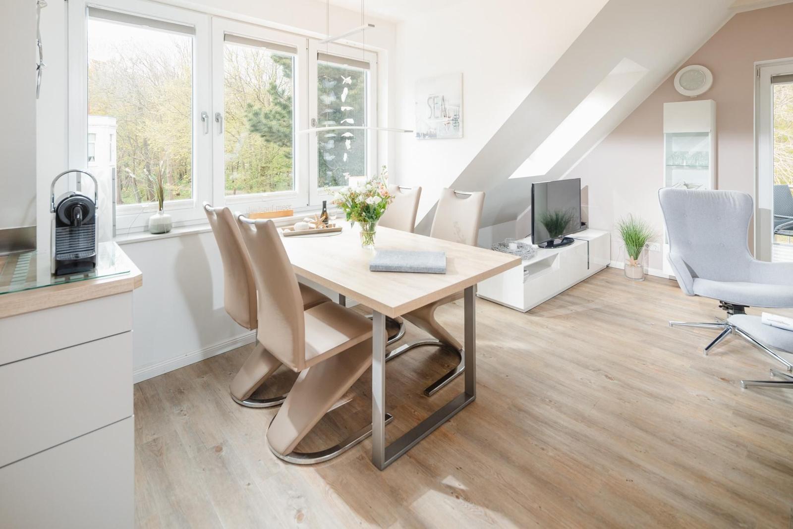 Esszimmer mit Tisch, Stühlen und TV-Ecke unter Dachschräge.