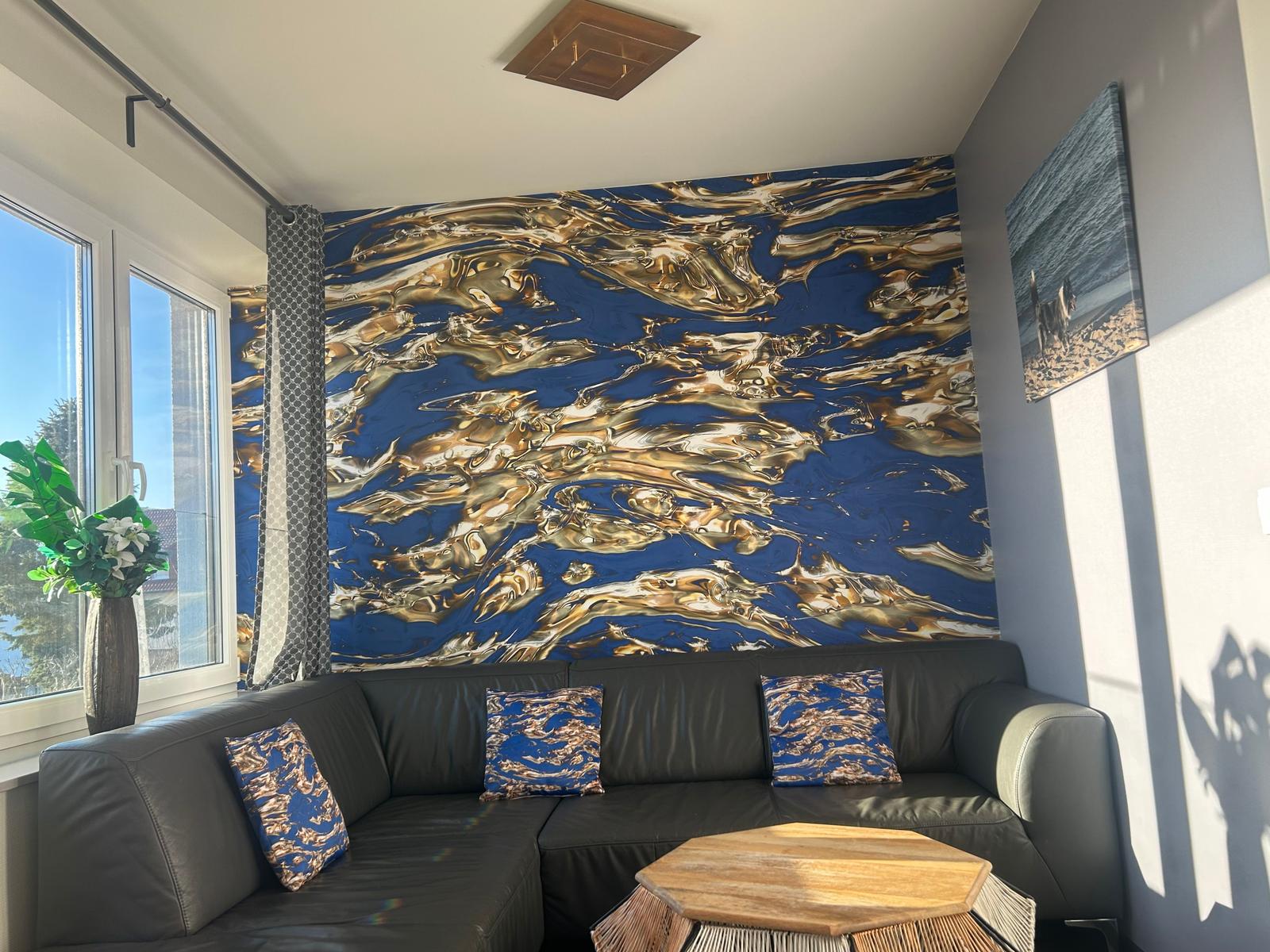 Wohnzimmer mit Sofa, Wandbild und Fenster. Möbel sind modern und schlicht.