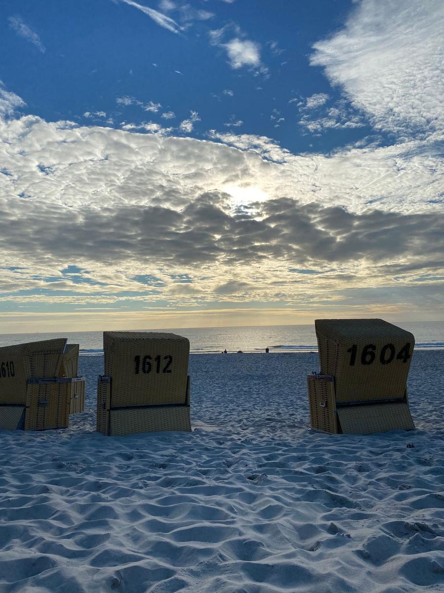 Strand mit Liegestühlen, nummeriert und Blick auf Meer und Himmel.