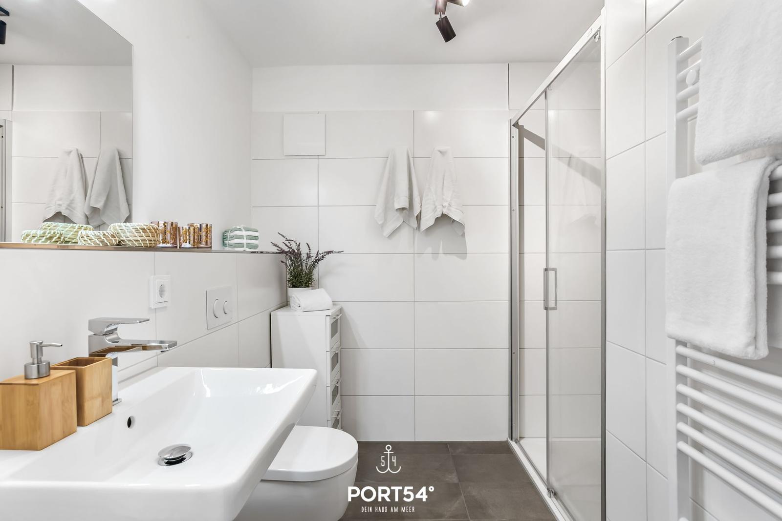 Badezimmer mit Dusche, Waschbecken und Heizkörper