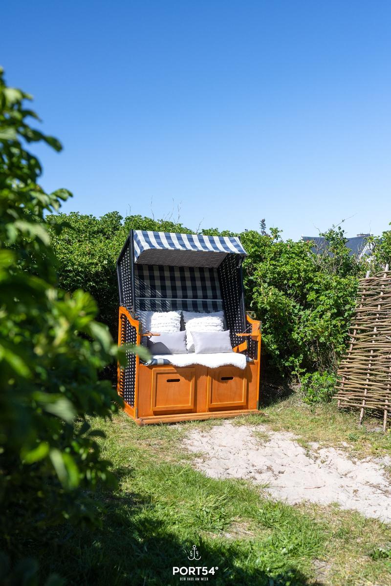 Hängesessel mit Streifenmarkise und Kissen im Garten