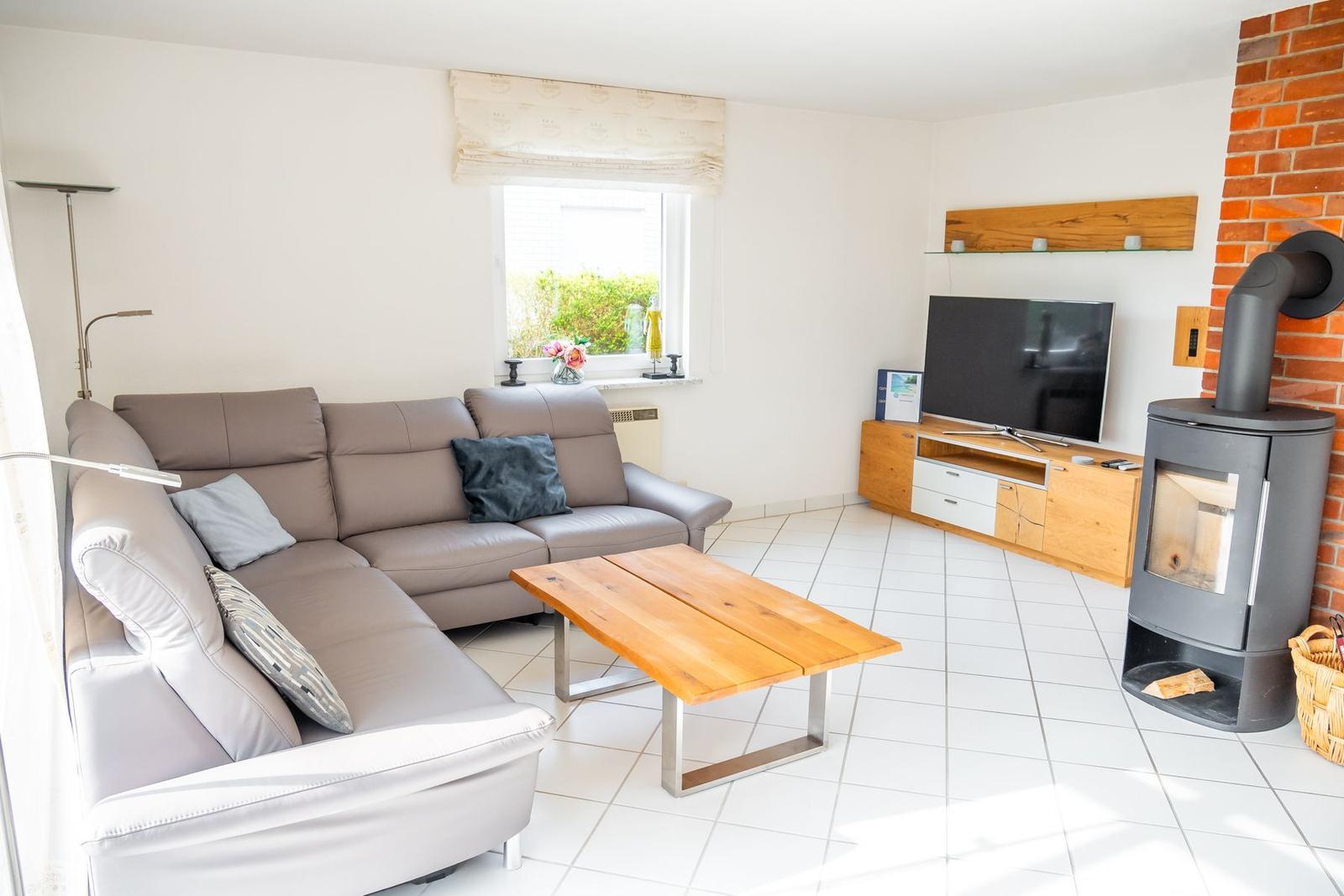 Wohnzimmer mit Sofa, Fernseher und Kaminofen.