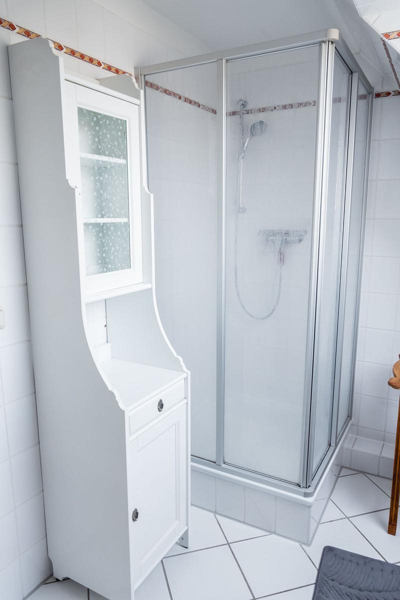 Badezimmer mit Dusche und weißem Schrank