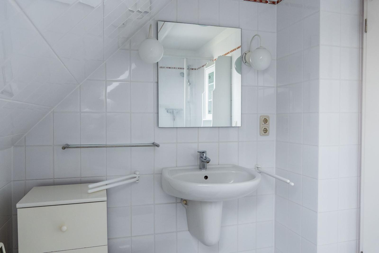 Badezimmer mit Waschbecken, Spiegel und Dusche.