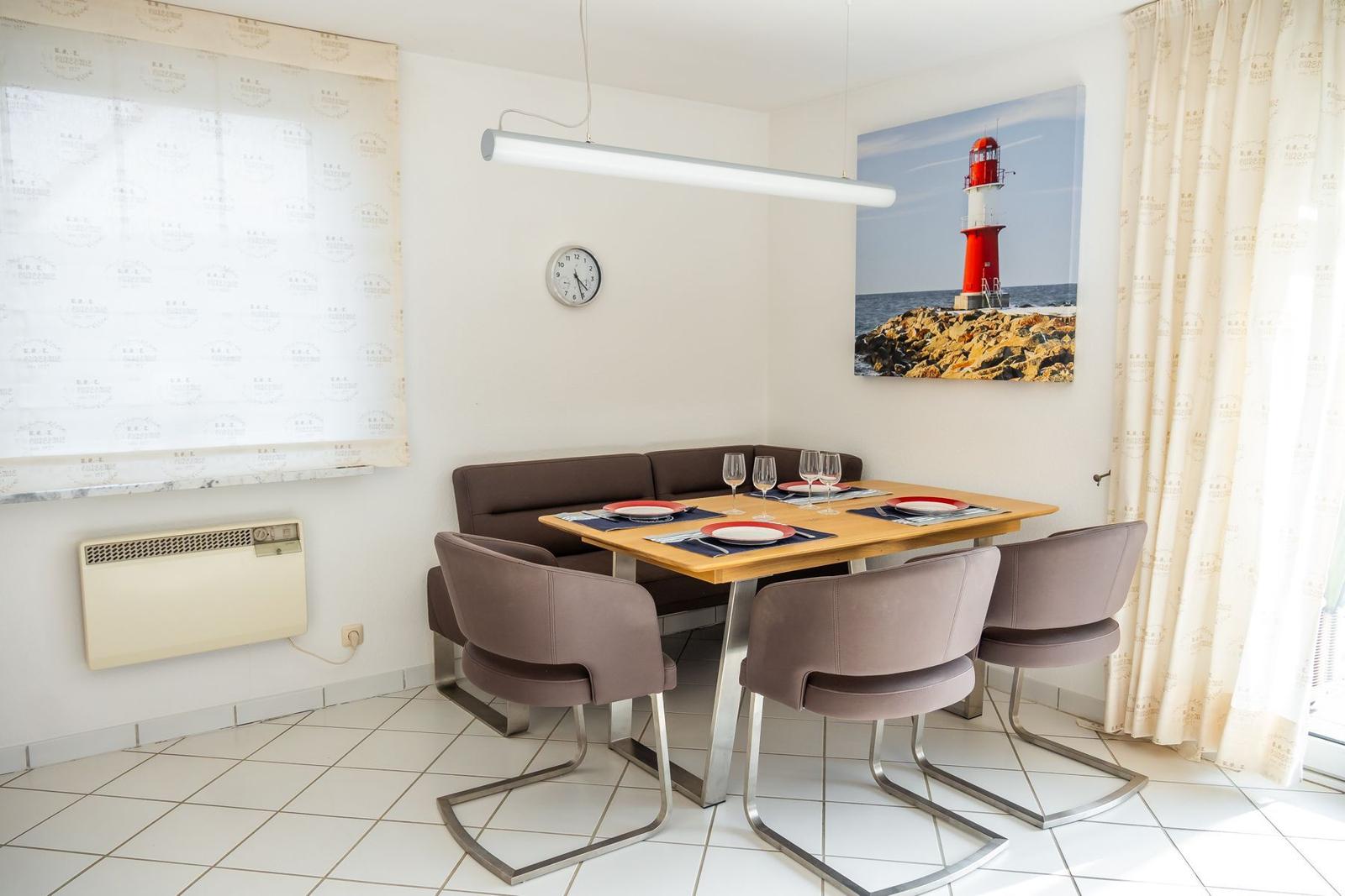 Esszimmer mit Tisch, Stühlen und Wandbild eines Leuchtturms.
