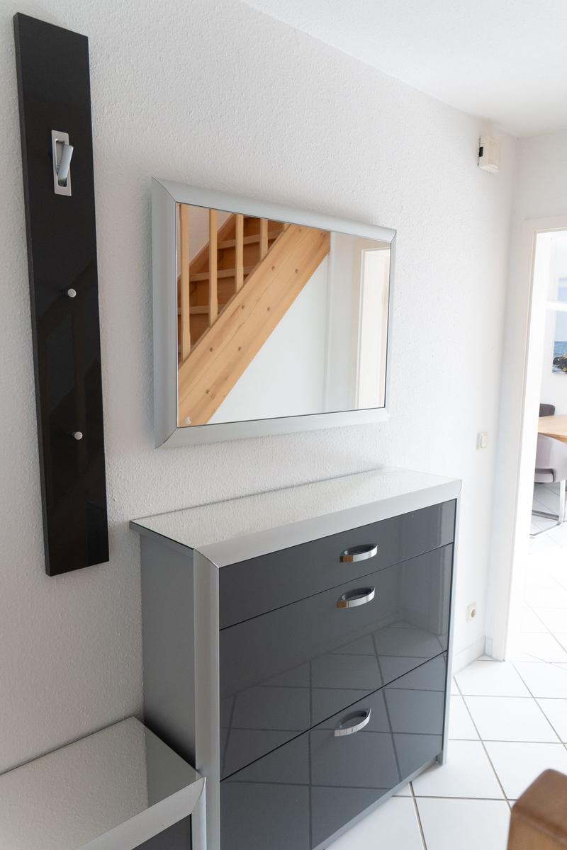 Schwarzer Schrank mit Spiegel und Holztreppe im Hintergrund