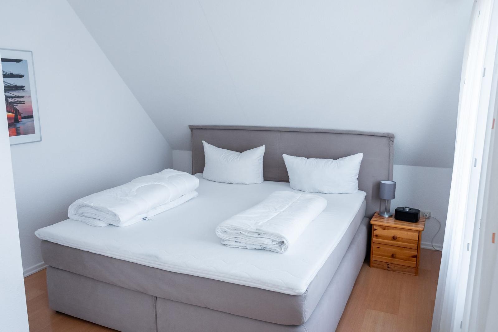Schlafzimmer mit Doppelbett, Nachttisch und Bild an der Wand.