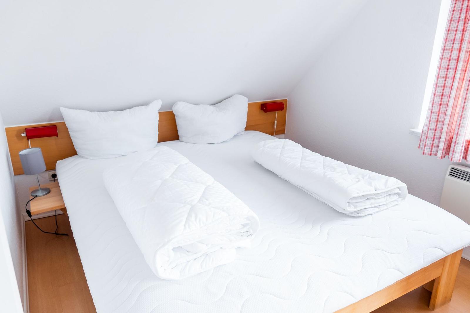 Ein Schlafzimmer mit einem Bett, zwei Kissen, einer Bettdecke und einer Nachttischlampe.