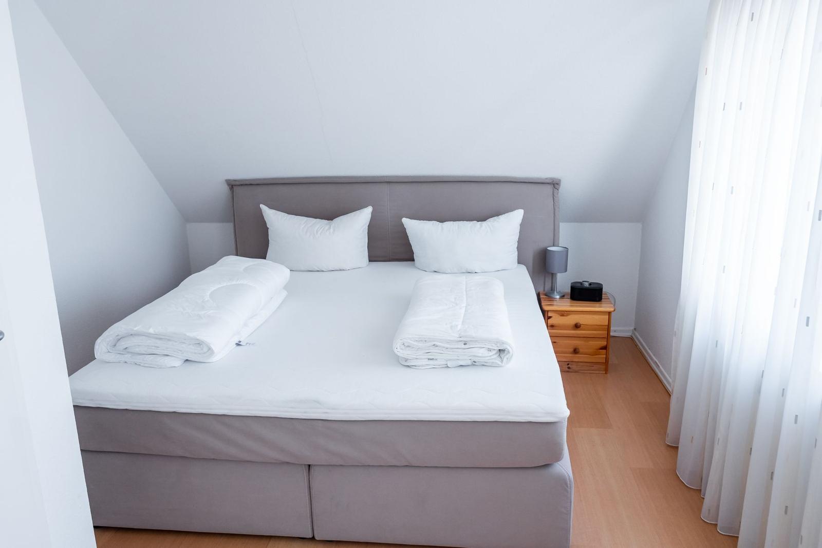 Schlafzimmer mit Doppelbett, Nachttisch und Fenster