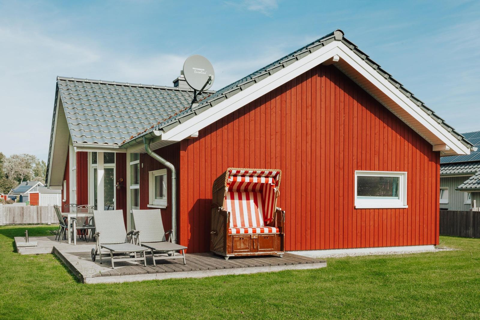 Rotes Holzhaus mit Terrasse, Strandkorb und Garten