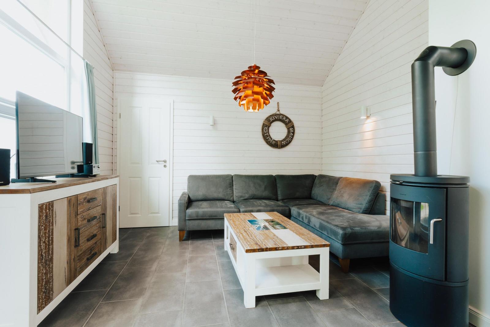 Wohnzimmer mit Sofa, Kamin und Fernseher an Wand