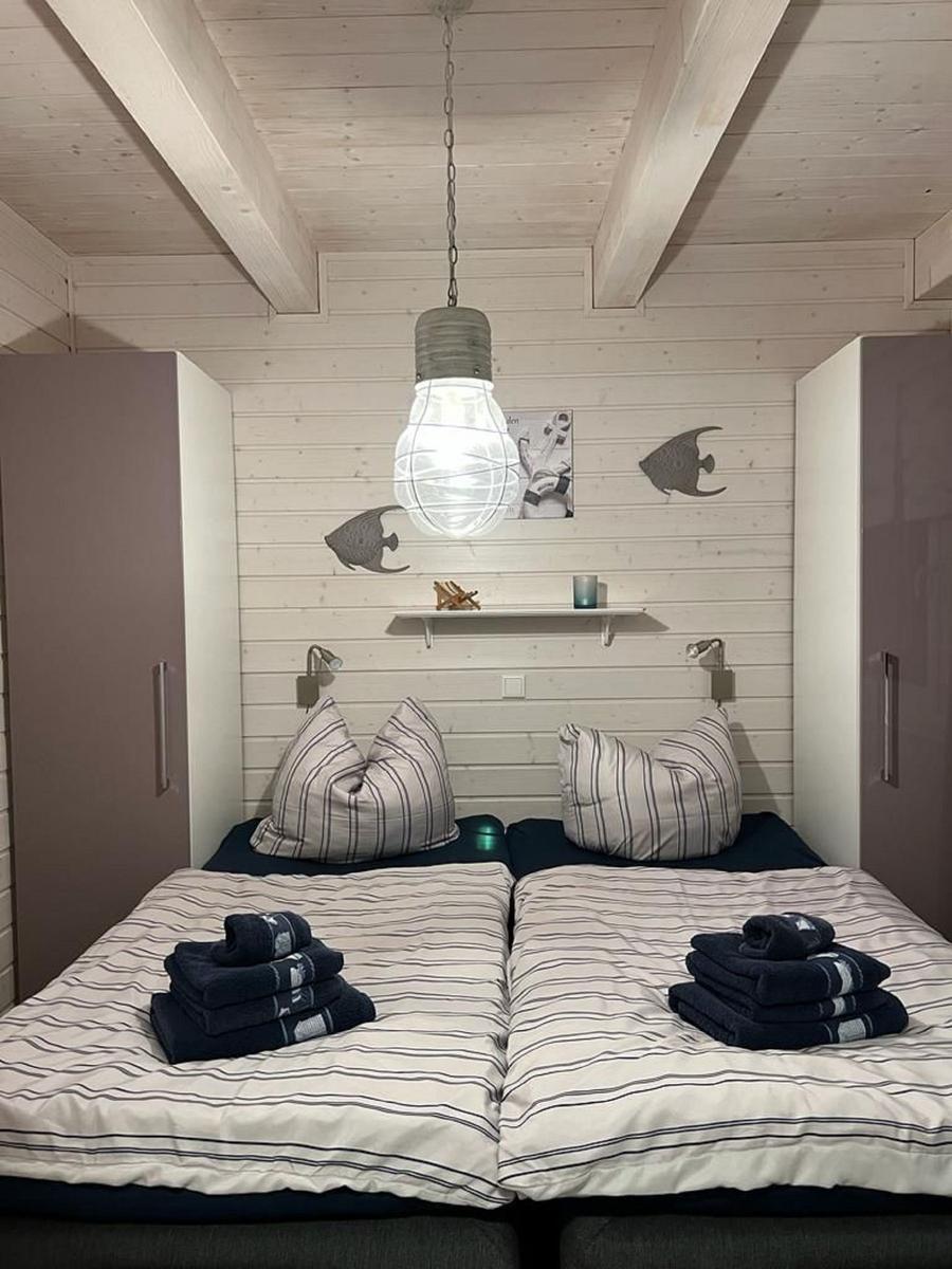 Zwei Betten mit gestreiften Bettwäsche und Handtüchern. Holzwand und Decke mit Fischdekoration.
