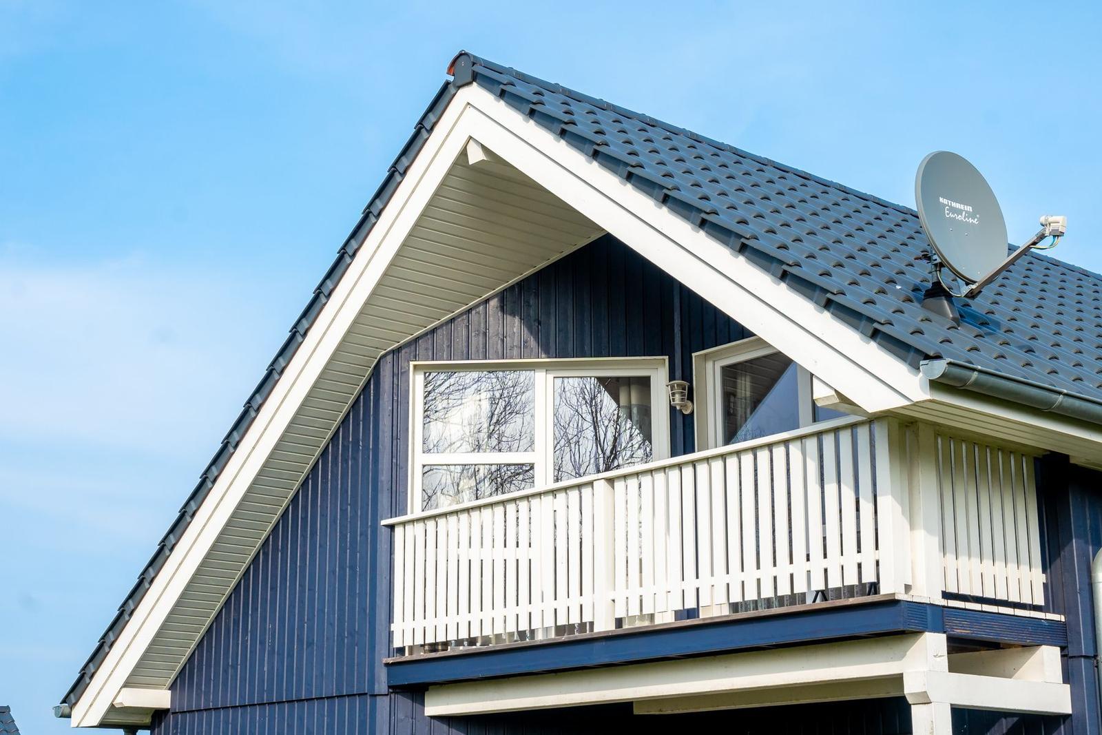 Dachgeschoss mit Balkon, Satellitenantenne und Fenstern.