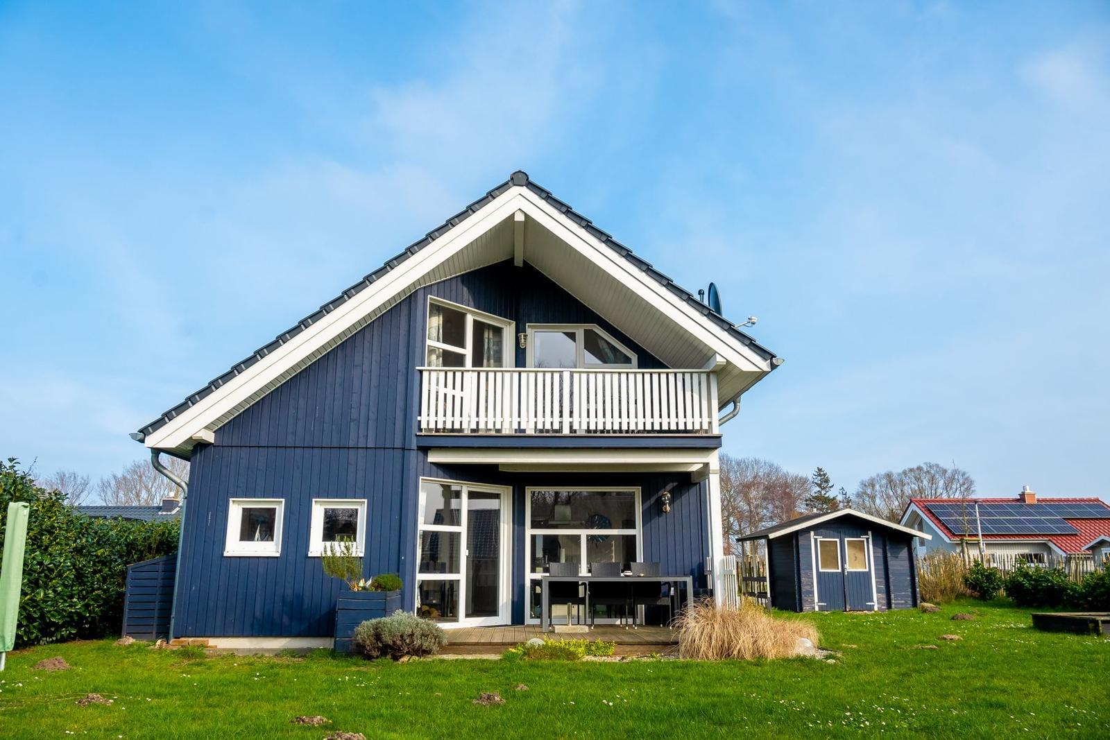 Blau gestrichenes Haus mit Balkon und Terrasse im Garten