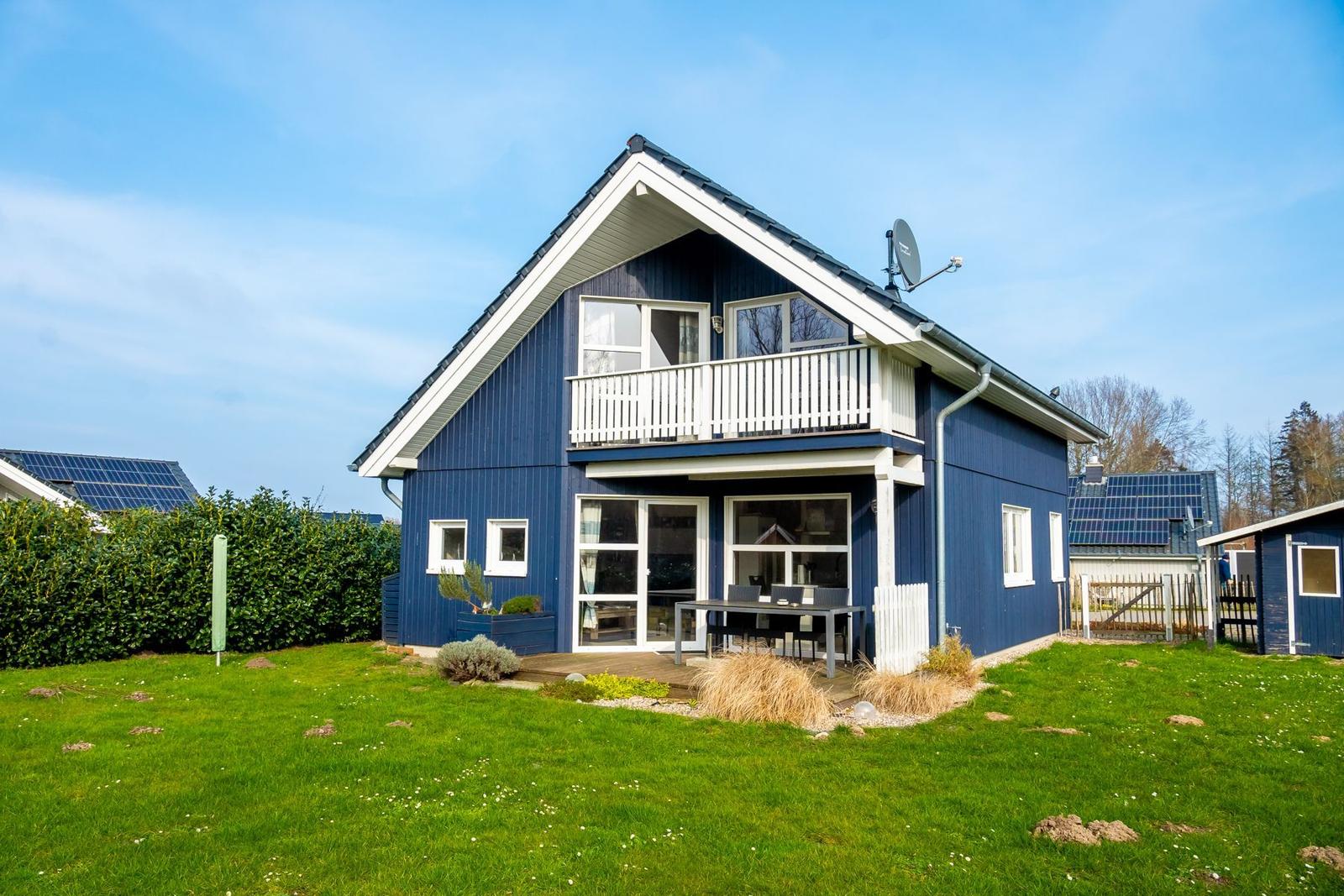 Blau gestrichenes Haus mit Balkon und Terrasse im Garten