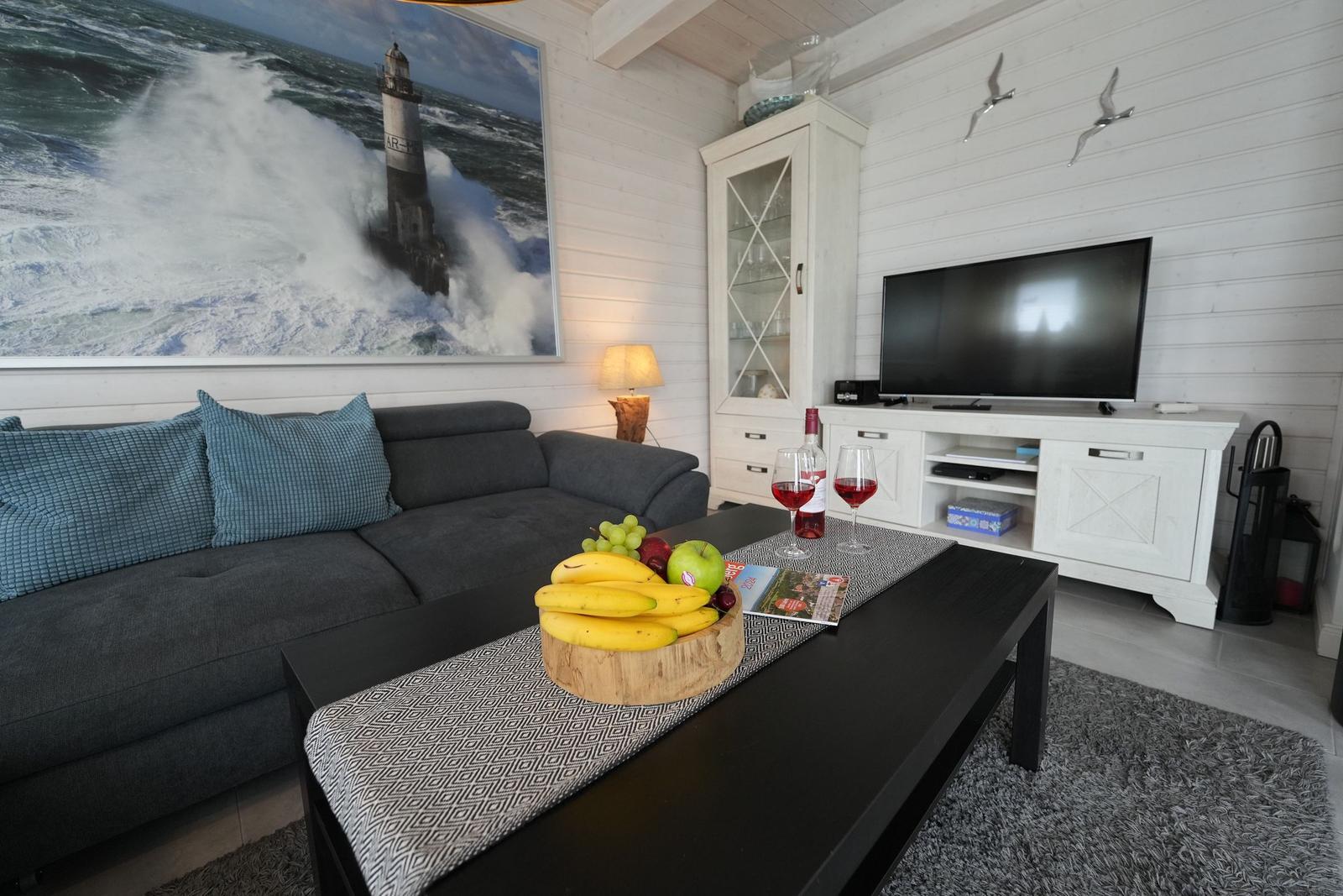Wohnzimmer mit Sofa, Fernseher und Küchenzeile.