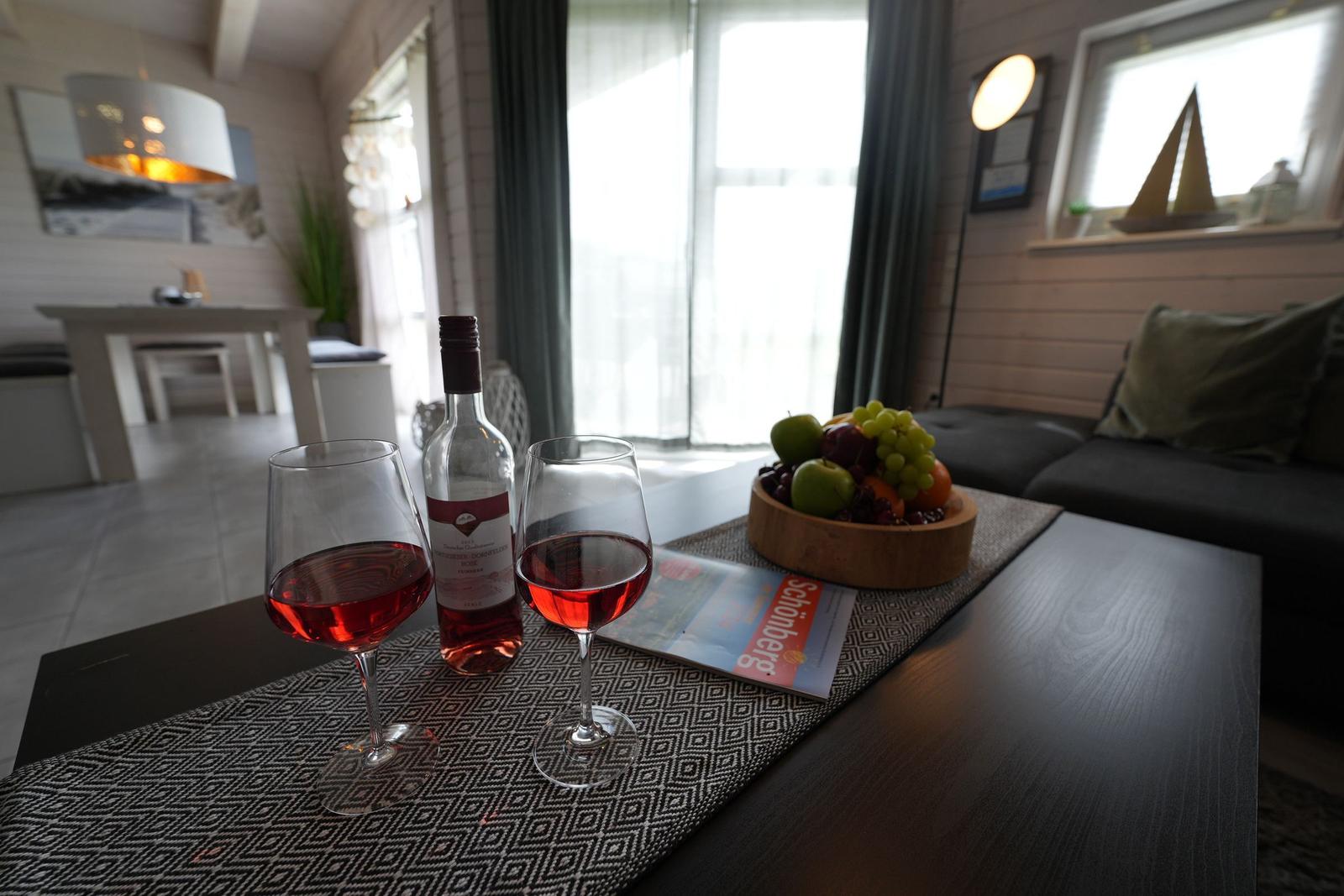 Auf dem Tisch stehen zwei Weingläser, eine Flasche Rosé und eine Obstschale.