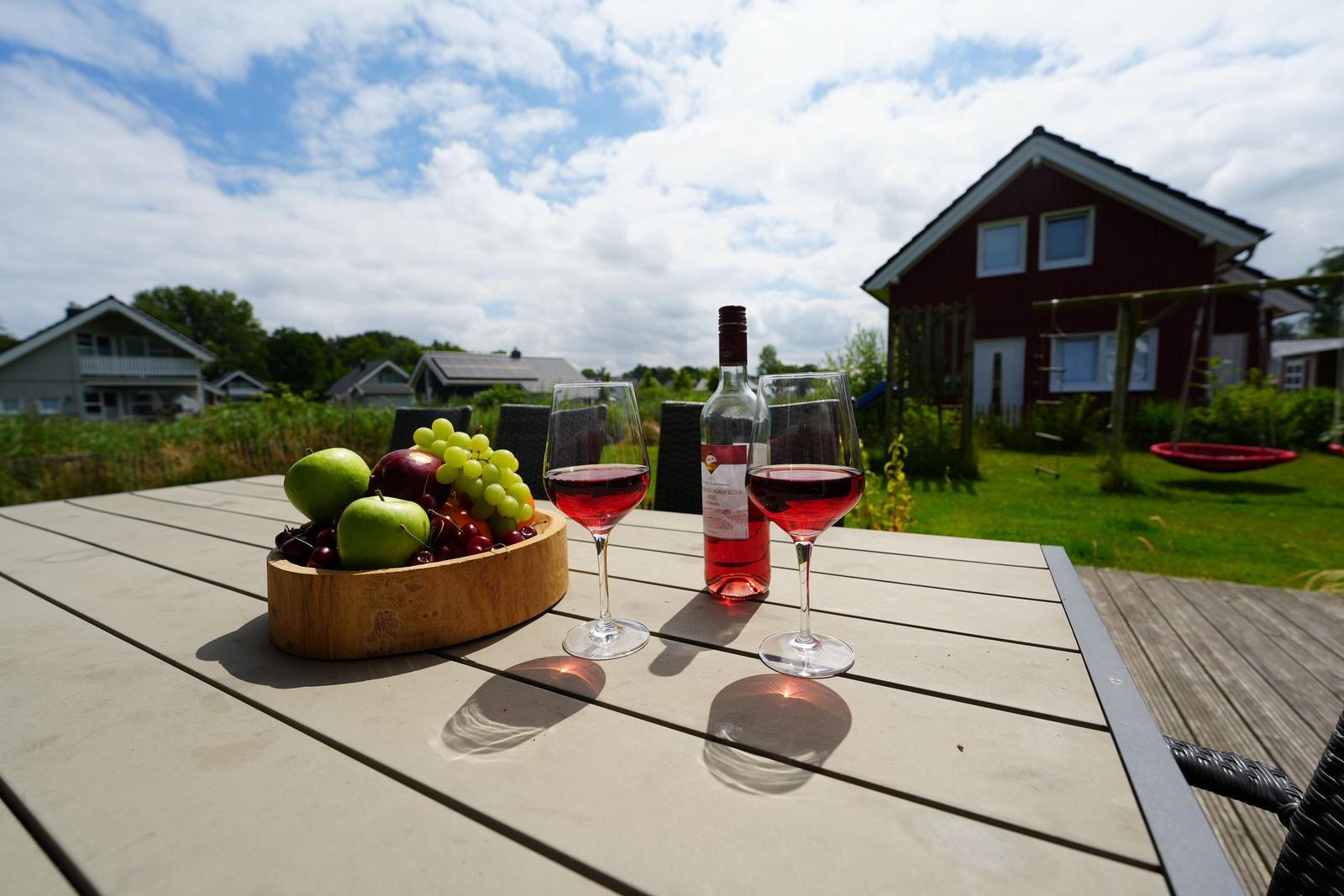 Tisch mit Wein, Obst und Blick auf Haus und Garten