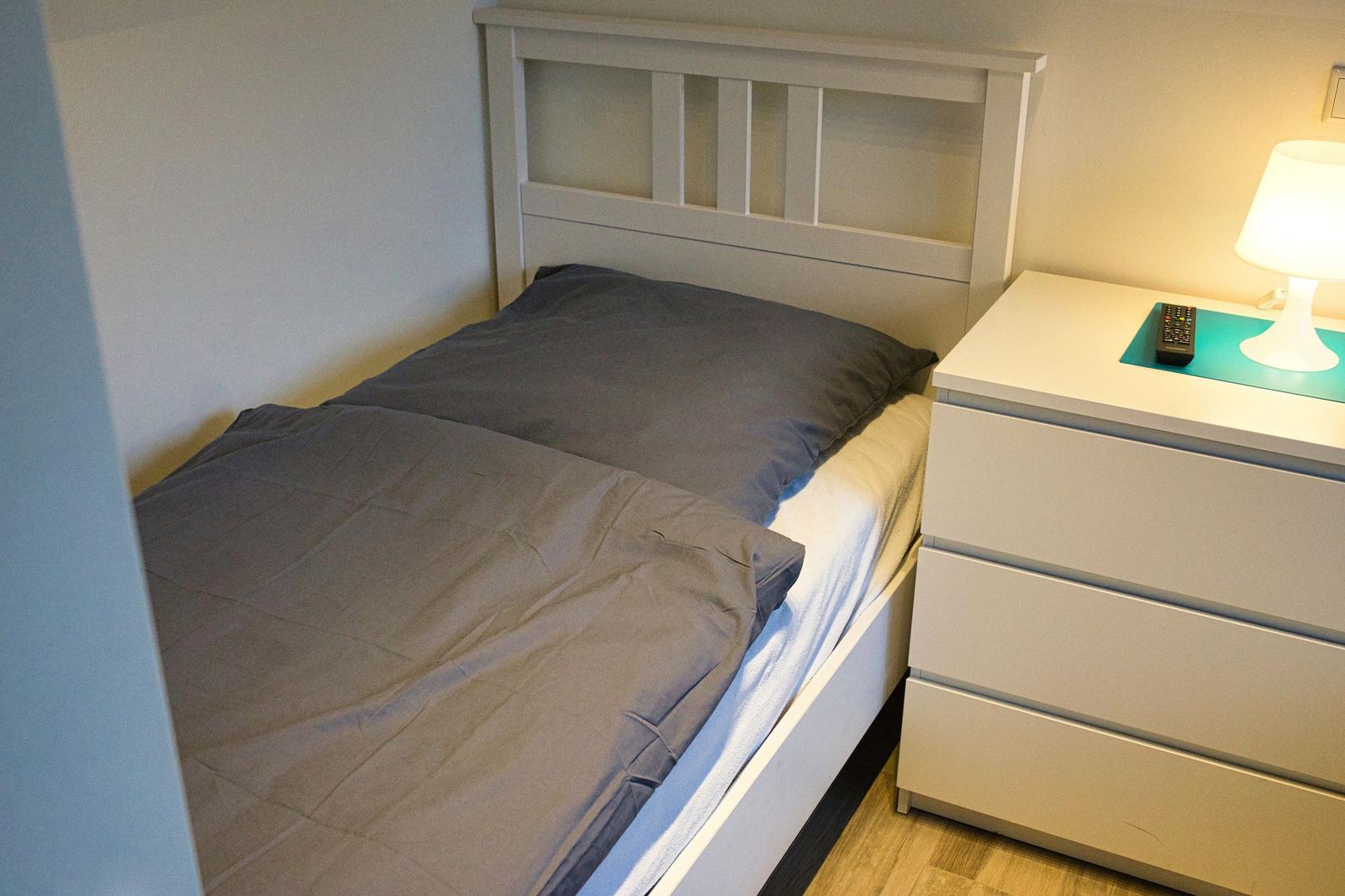 Schlafzimmer mit Bett, Nachttisch und Lampe.