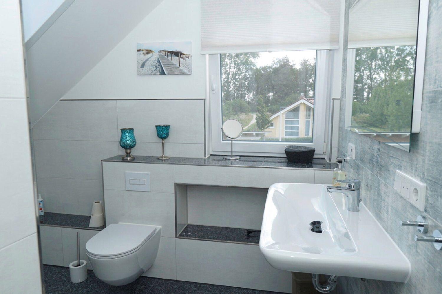 Badezimmer mit Waschbecken, Toilette und Fensterblick