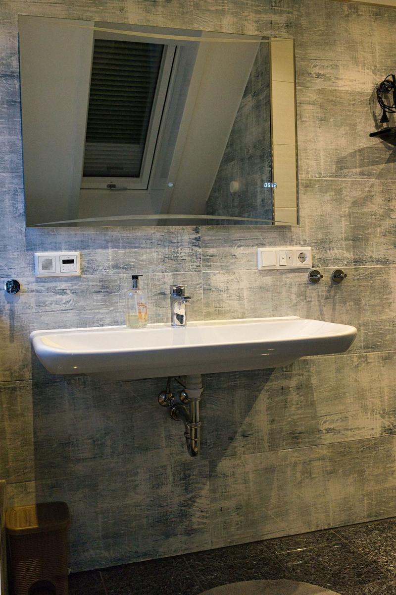Waschbecken mit Spiegel und Duschkopf an der Wand