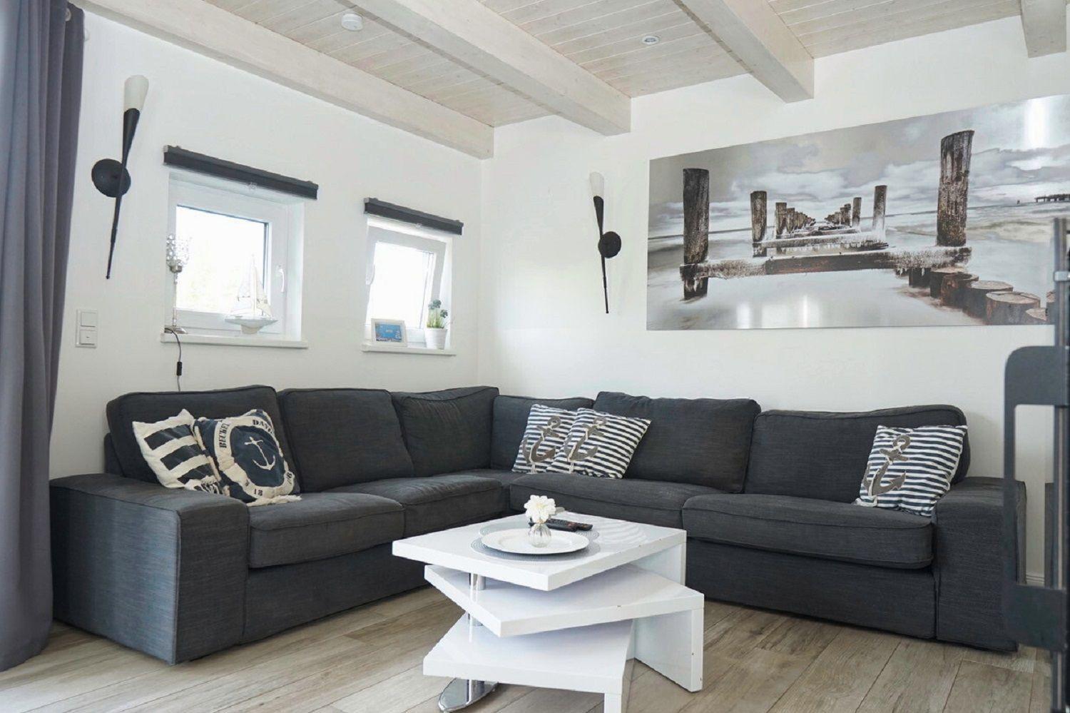 Ein Wohnzimmer mit grauem Sofa, weißem Couchtisch und Wandbild mit Steg.