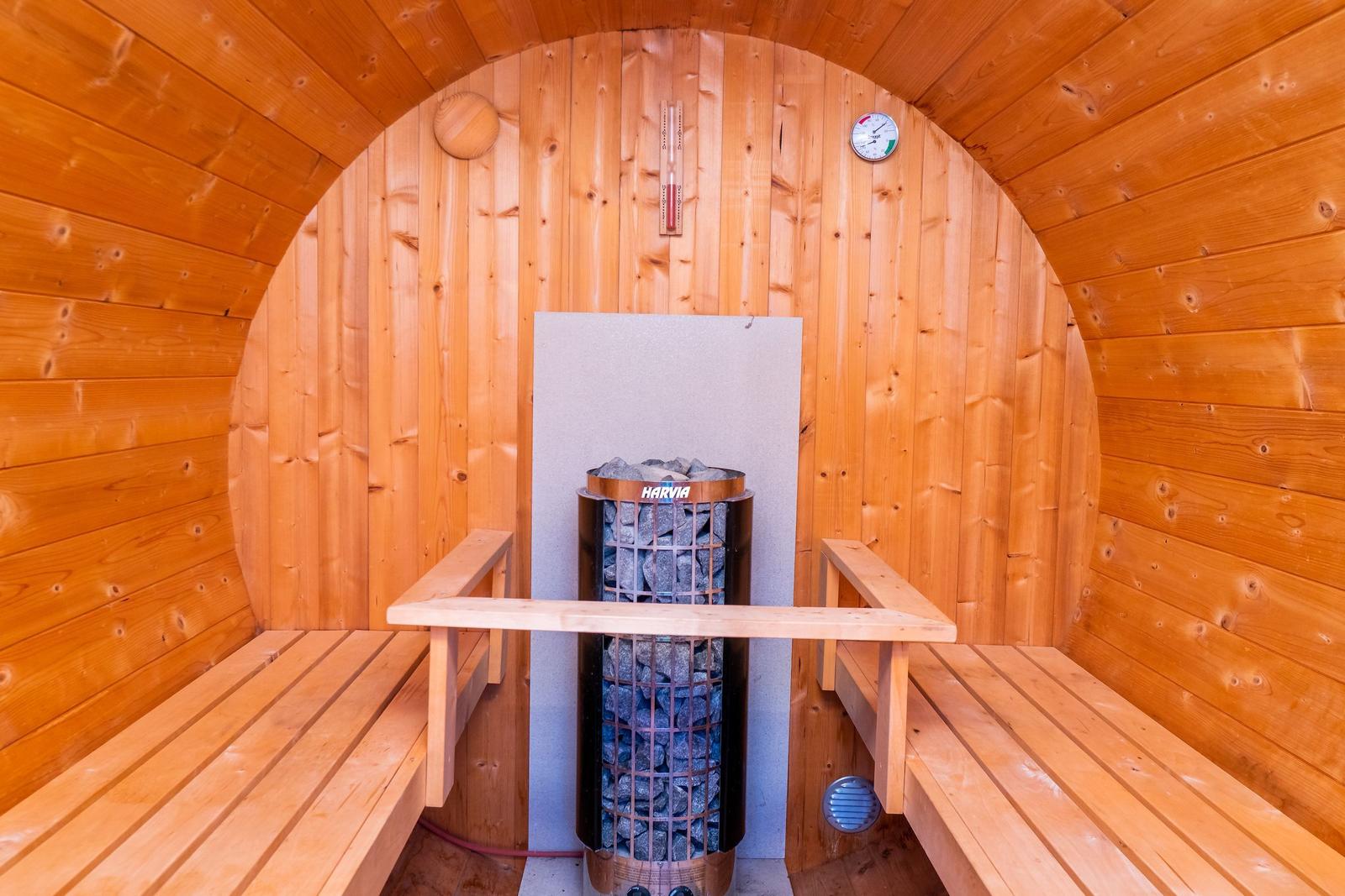 Sauna mit Holzbank und Heizung. Thermometer an der Wand.