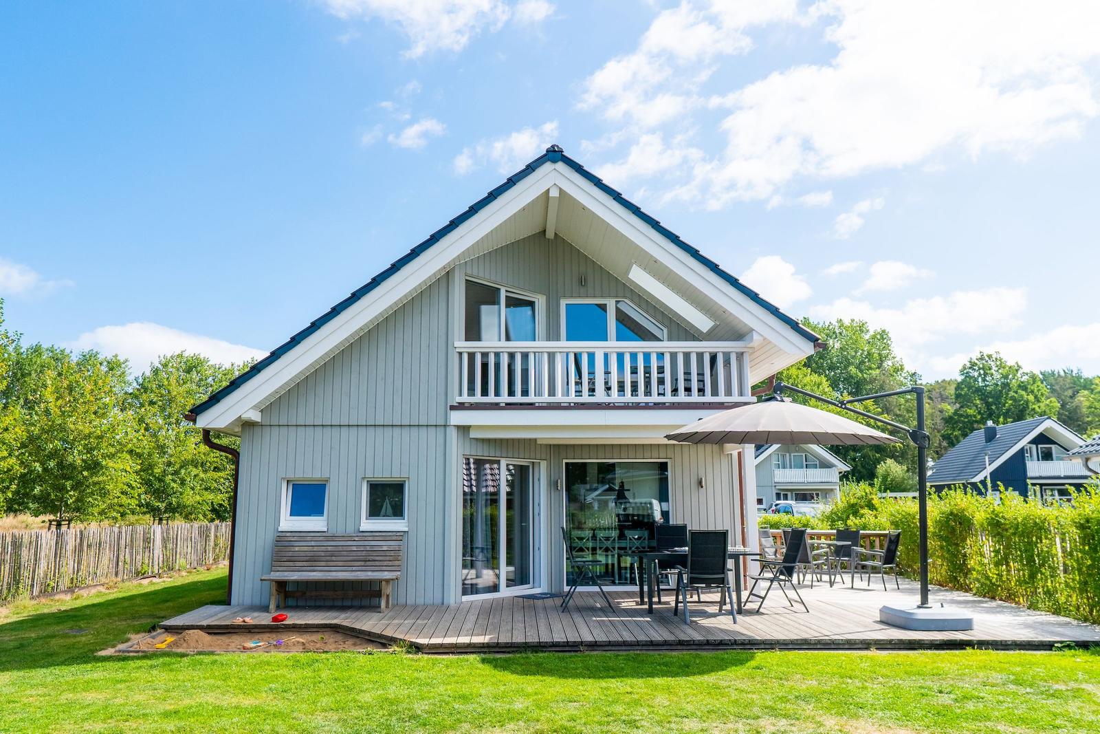 Haus mit Terrasse, Garten und Sitzgelegenheiten unter freiem Himmel.