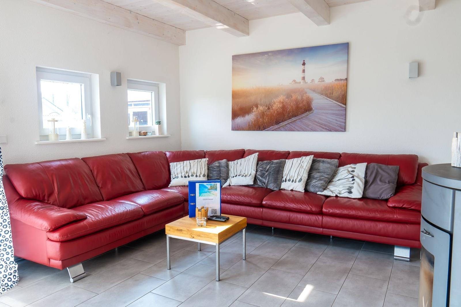 Ein Wohnzimmer mit rotem Sofa, Holztisch und Wandbild mit Leuchtturm.