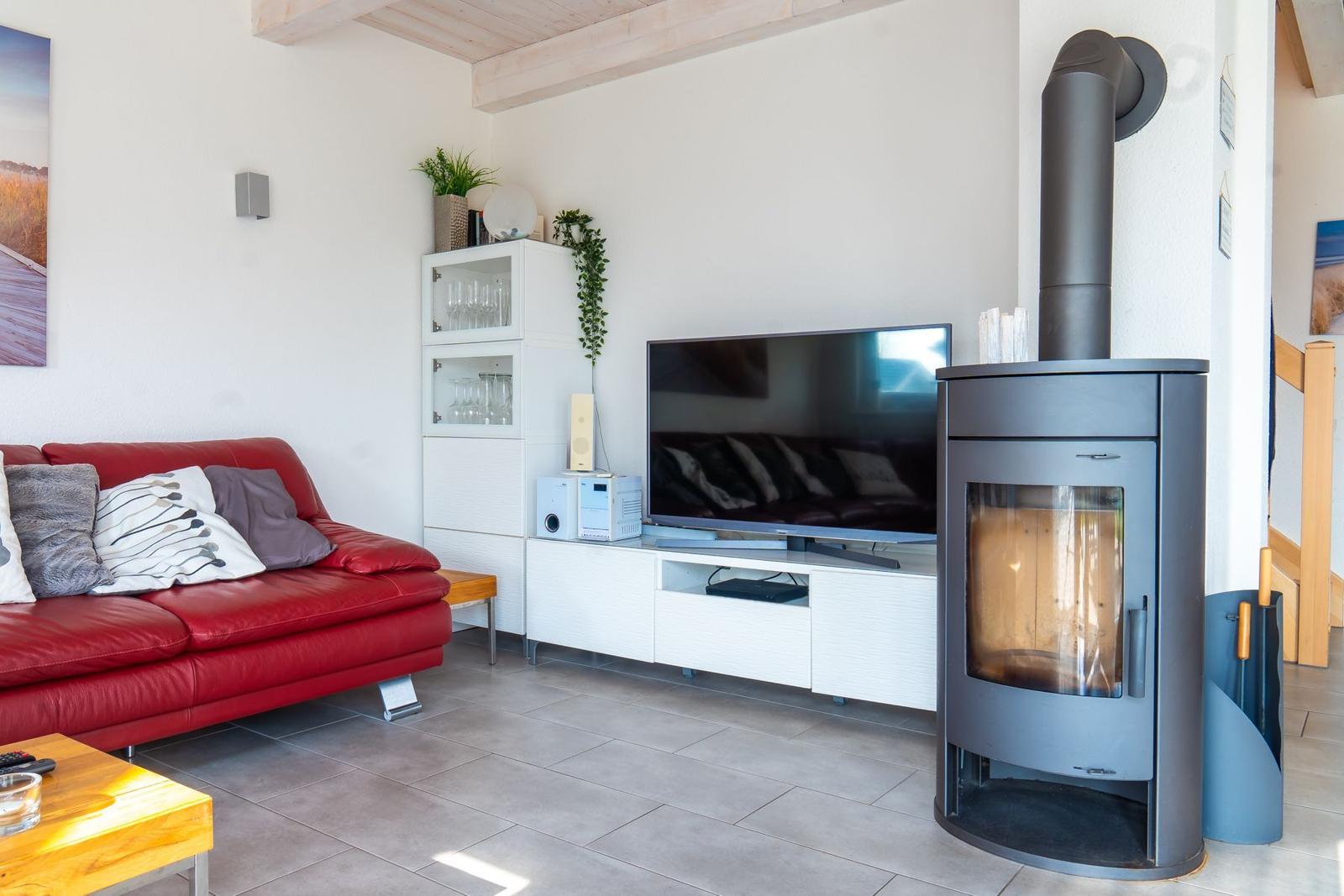 Ein Wohnzimmer mit rotem Sofa, TV und Kaminofen.