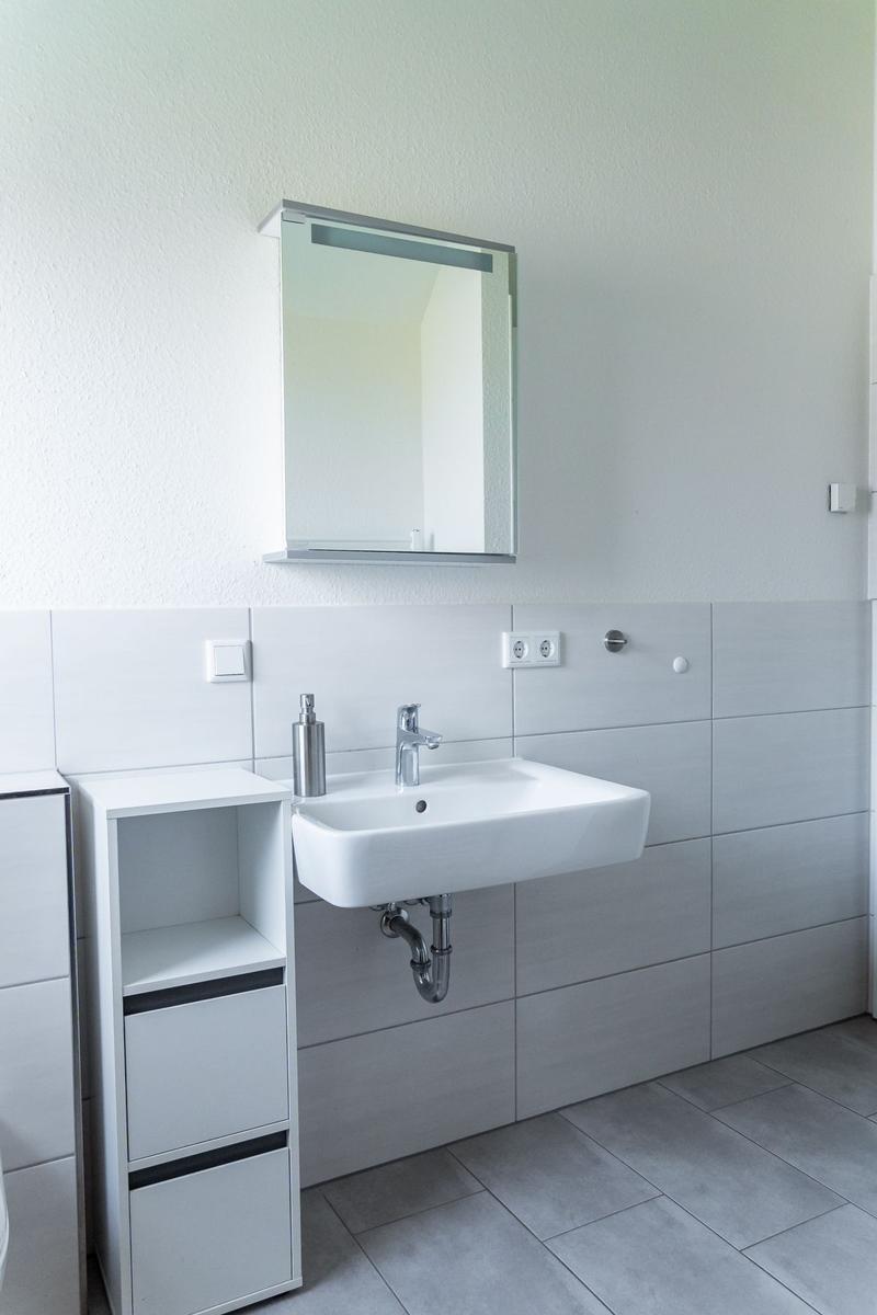 Badezimmer mit Waschbecken, Spiegelschrank und Unterschrank.