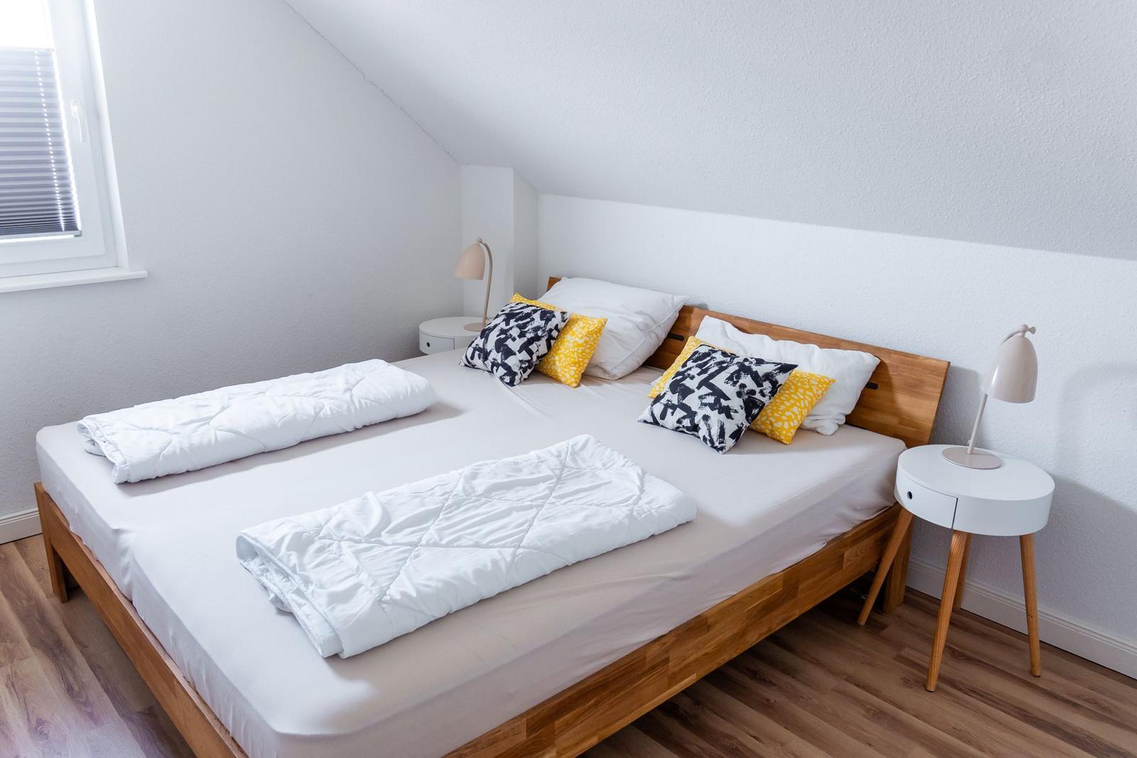 Schlafzimmer mit Doppelbett, Holzboden und zwei Nachttischen.