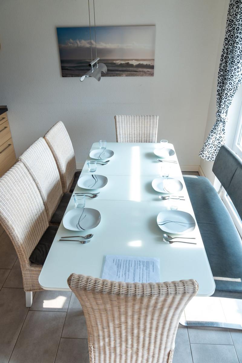 Esstisch mit sechs Stühlen und Platz für sechs Personen. Wandbild und Fenster mit Vorhang.